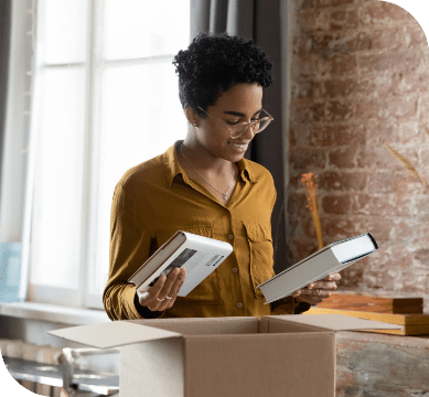 A person looking through books from  a box. 